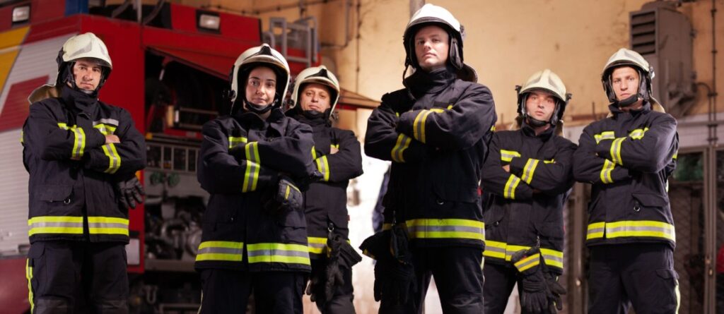 Firefighters wearing flame-resistant protective coveralls